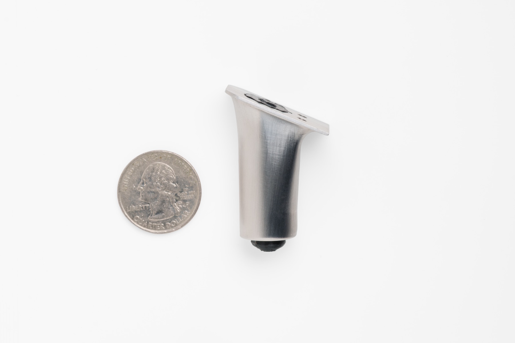 THYS heel mechanism, fully collapsed, beside a U.S. quarter for scale