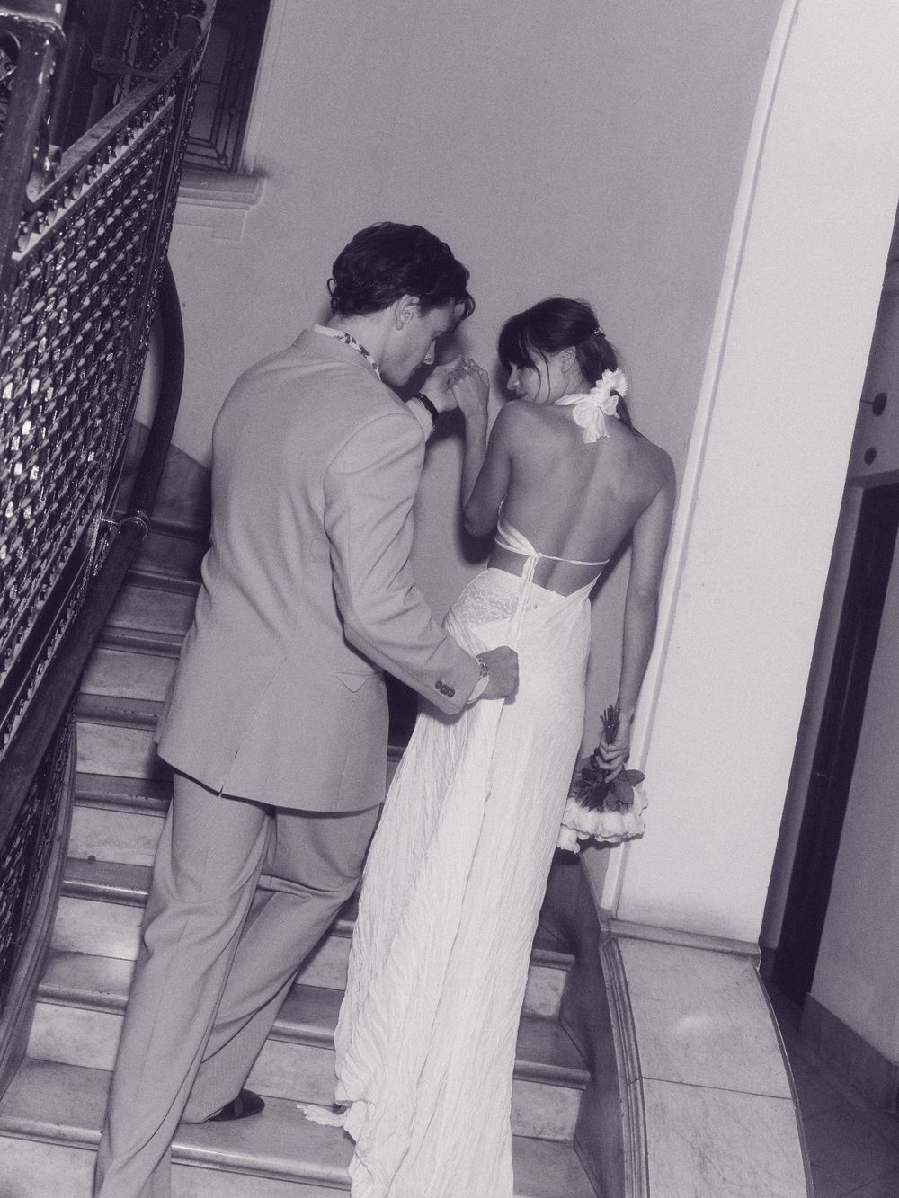 A couple in evening clothes pausing on a marble staircase