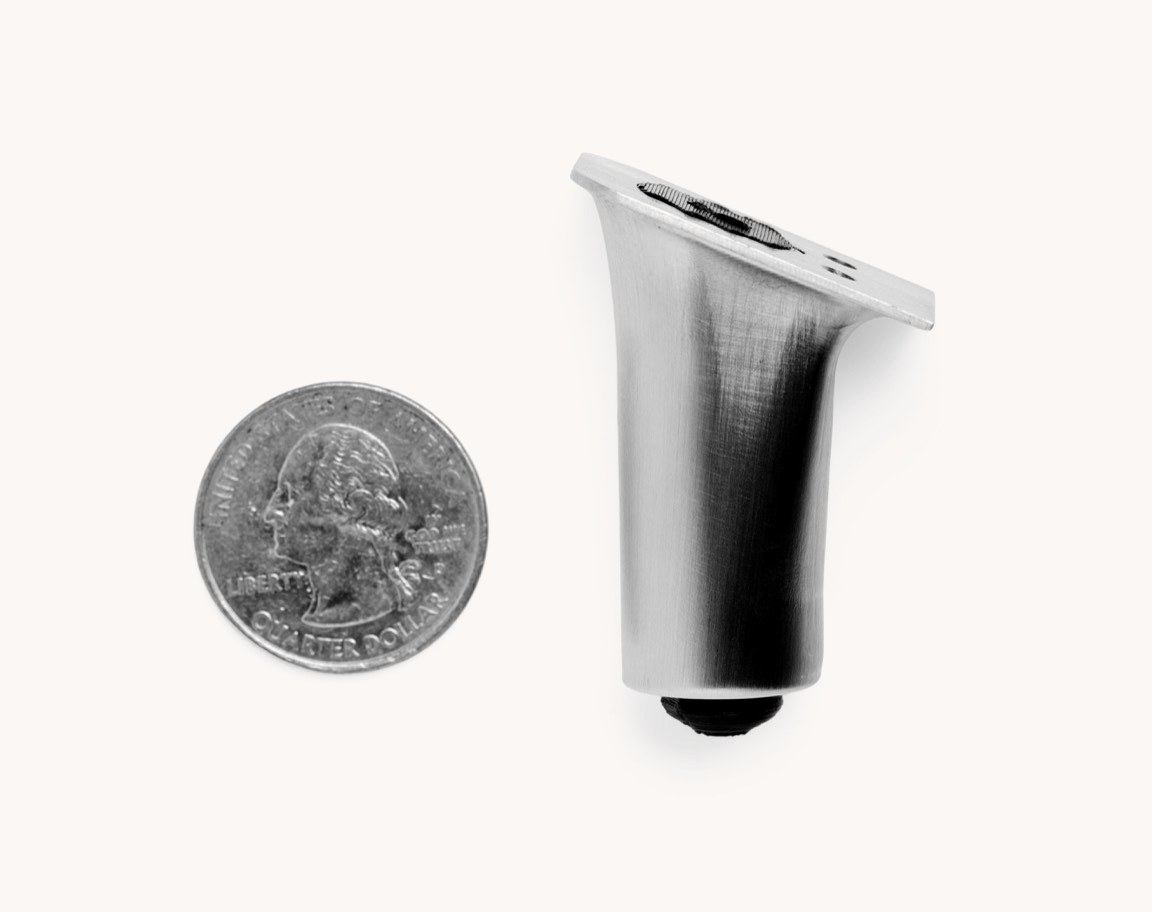 The THYS heel mechanism, fully collapsed, beside a U.S. quarter for scale