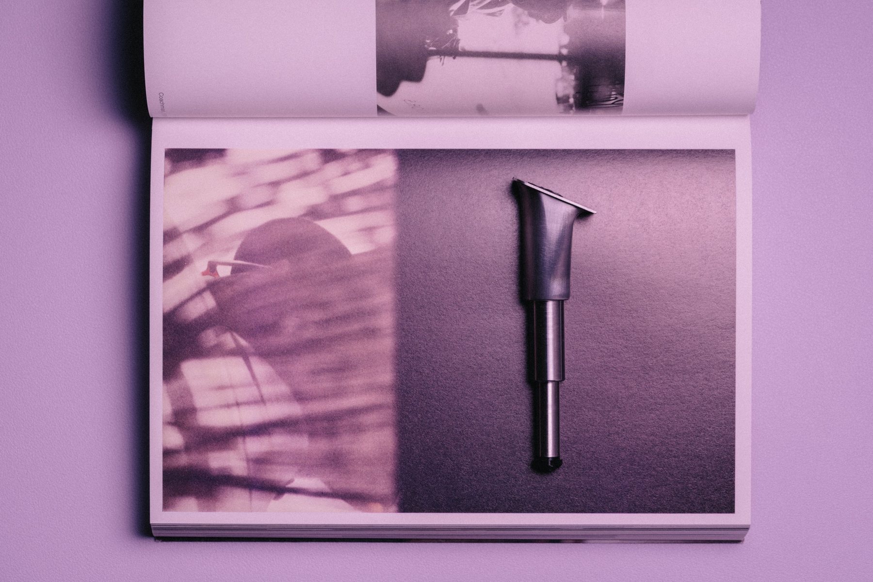 The THYS heel mechanism laid on the page of an open magazine, in lilac light